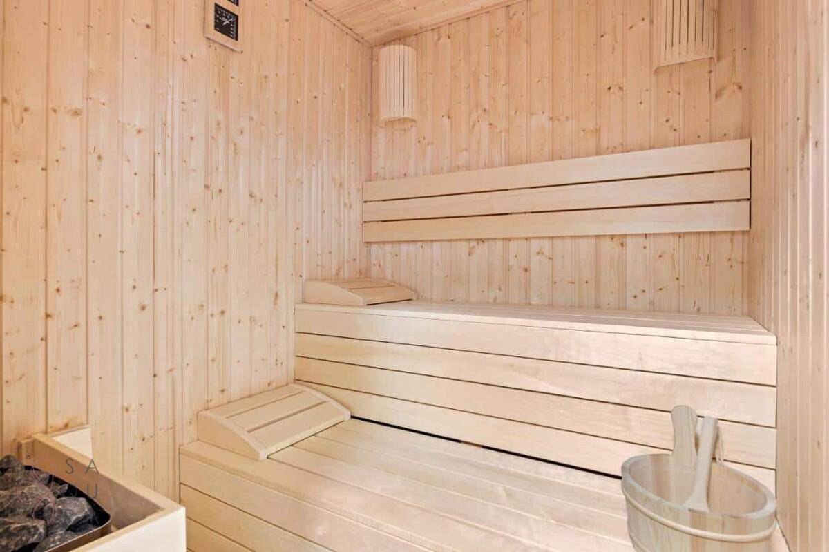 Helle Holzsauna mit traditionellen Bänken und Saunaofen für Entspannung.