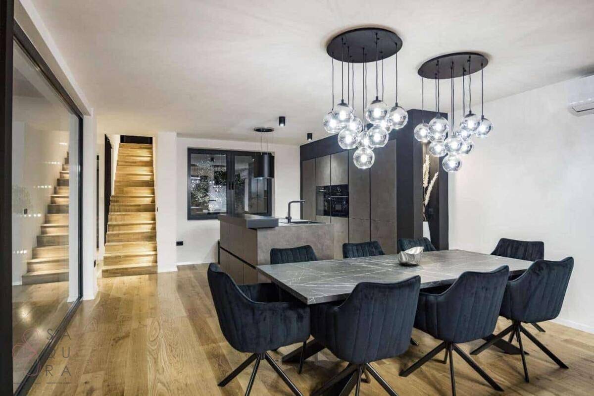 Offener Essbereich mit modernem Tisch, Designerleuchten und Blick auf die Treppe.