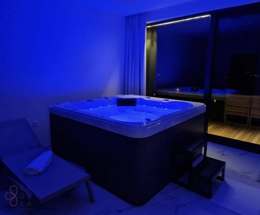 Entspannungsraum mit beleuchtetem Whirlpool und Blick nach draußen.