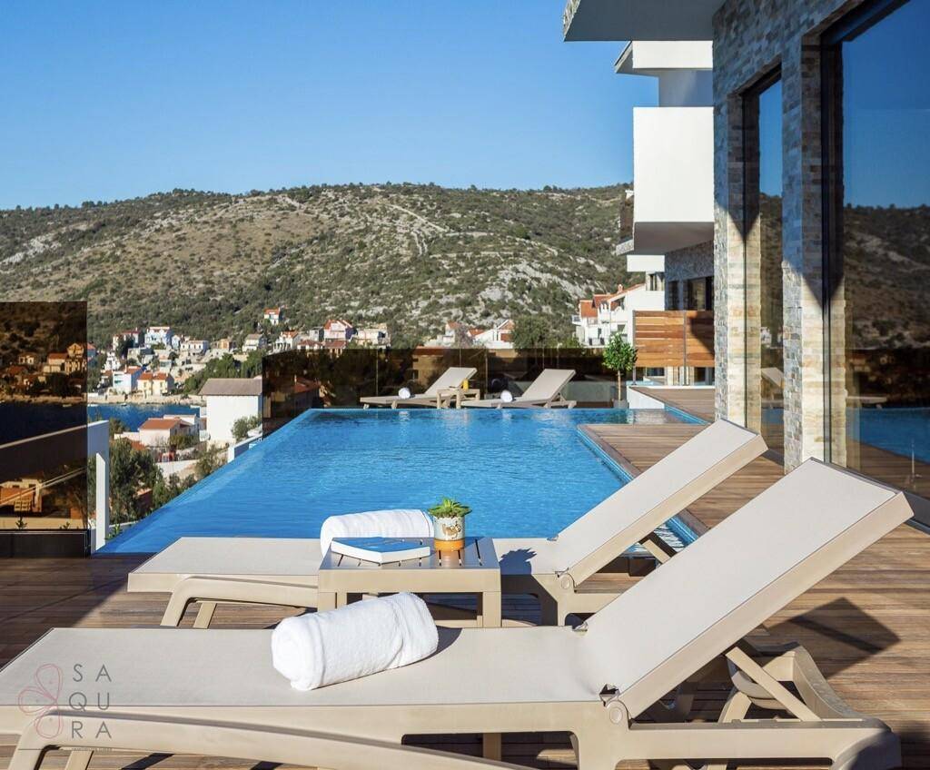 Entspannungsbereich auf dem Holzdeck mit Sonnenliegen und Infinity-Pool.