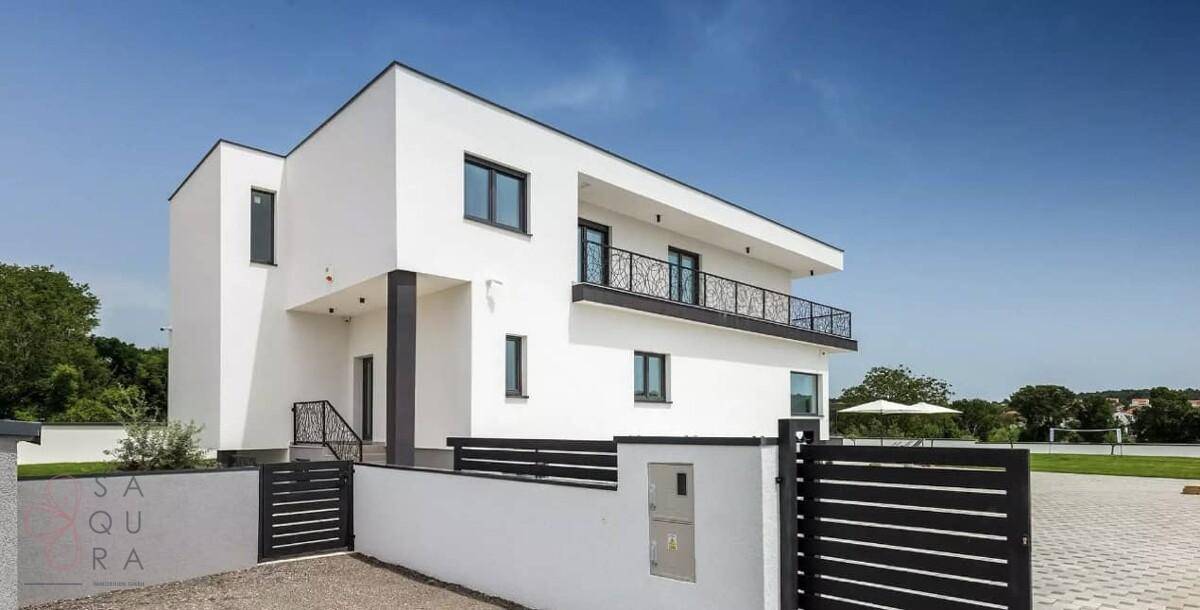Seitliche Ansicht der modernen weißen Villa mit klaren Linien und Eingangsbereich.