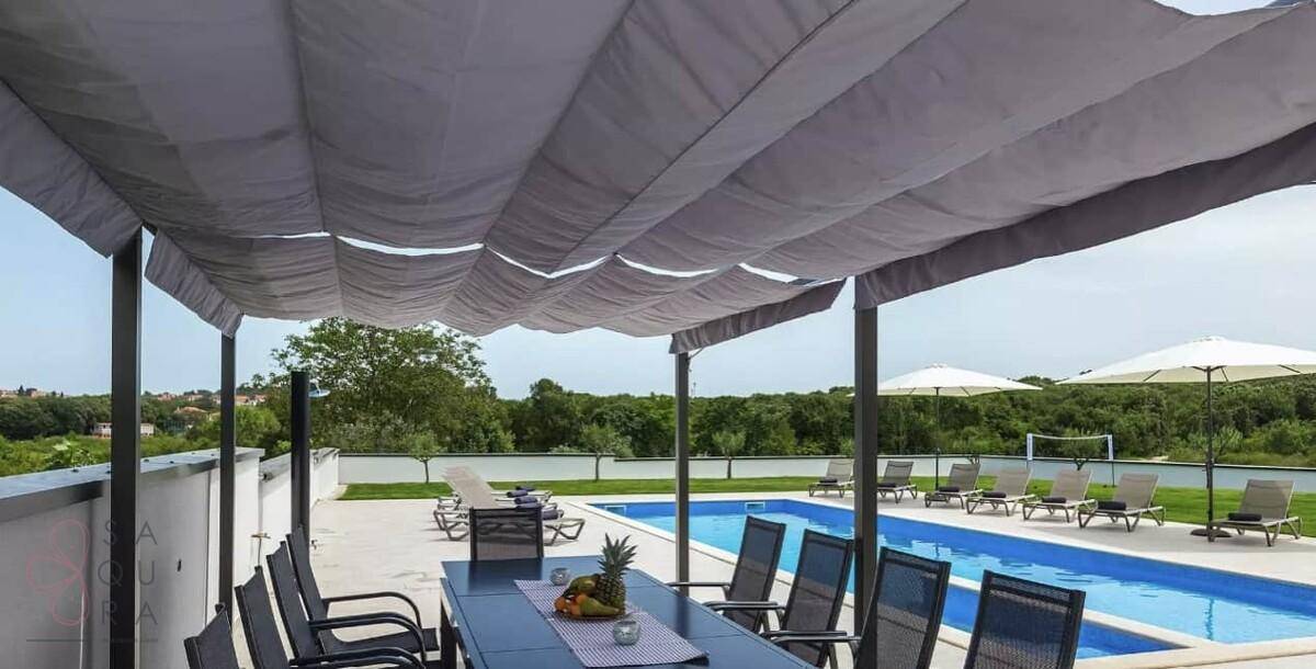Geräumiger überdachter Essbereich im Freien mit Blick auf den Pool und die grüne Landschaft.