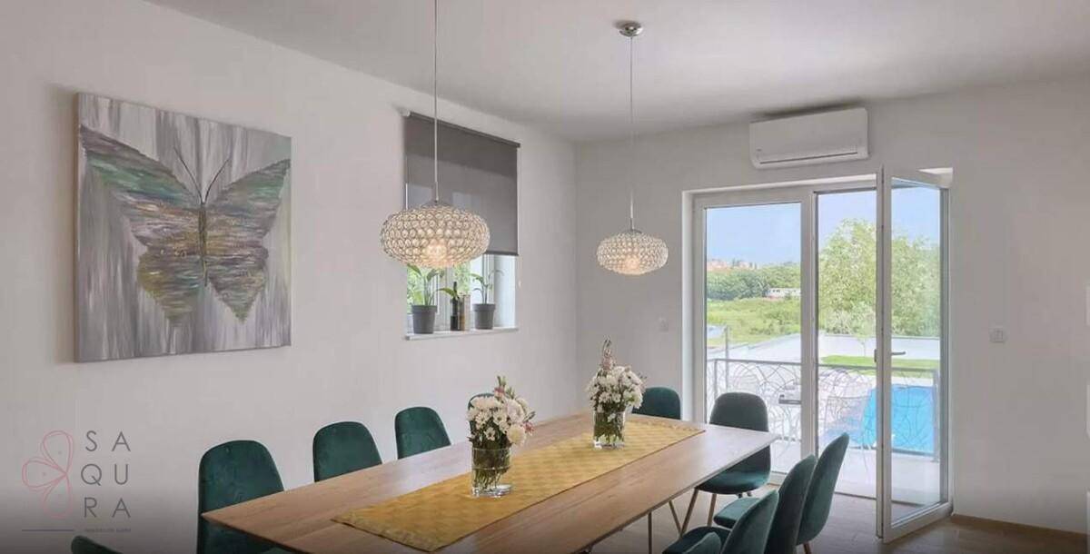 Heller Essbereich mit modernem Holztisch, grünen Stühlen und Zugang zum Balkon.