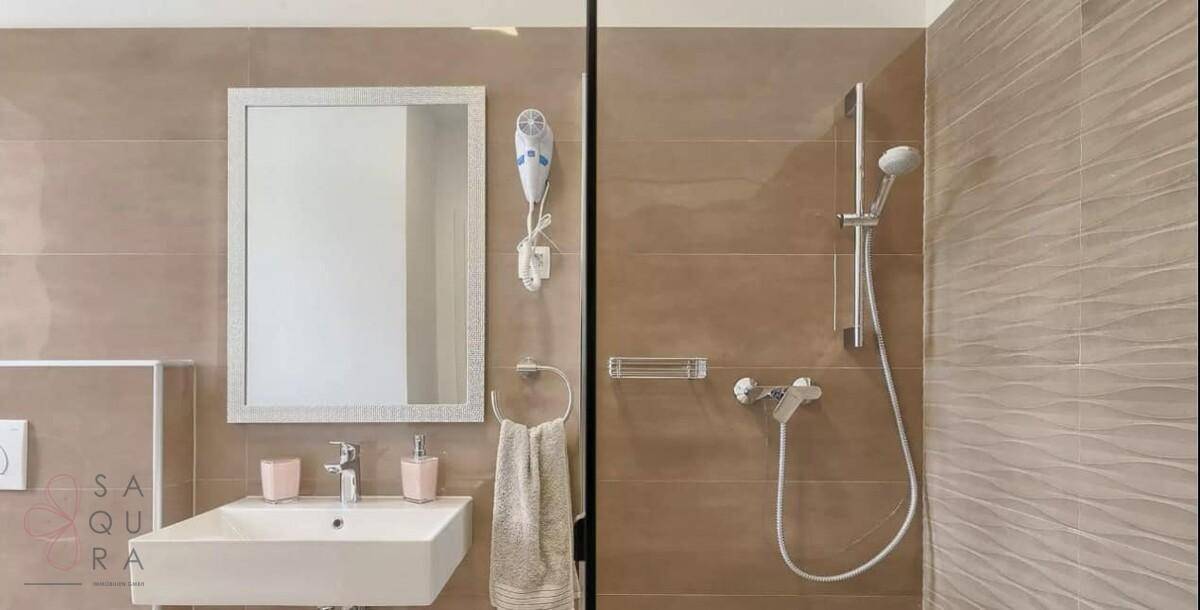Modernes Badezimmer mit Dusche, Einzelwaschbecken und braunen Fliesen.