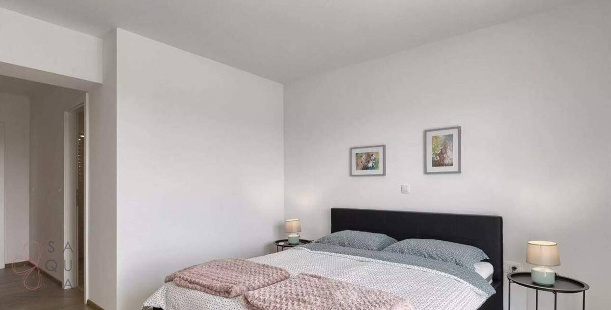 Helles Schlafzimmer mit Doppelbett, minimalistischer Einrichtung und zwei kleinen Bildern.