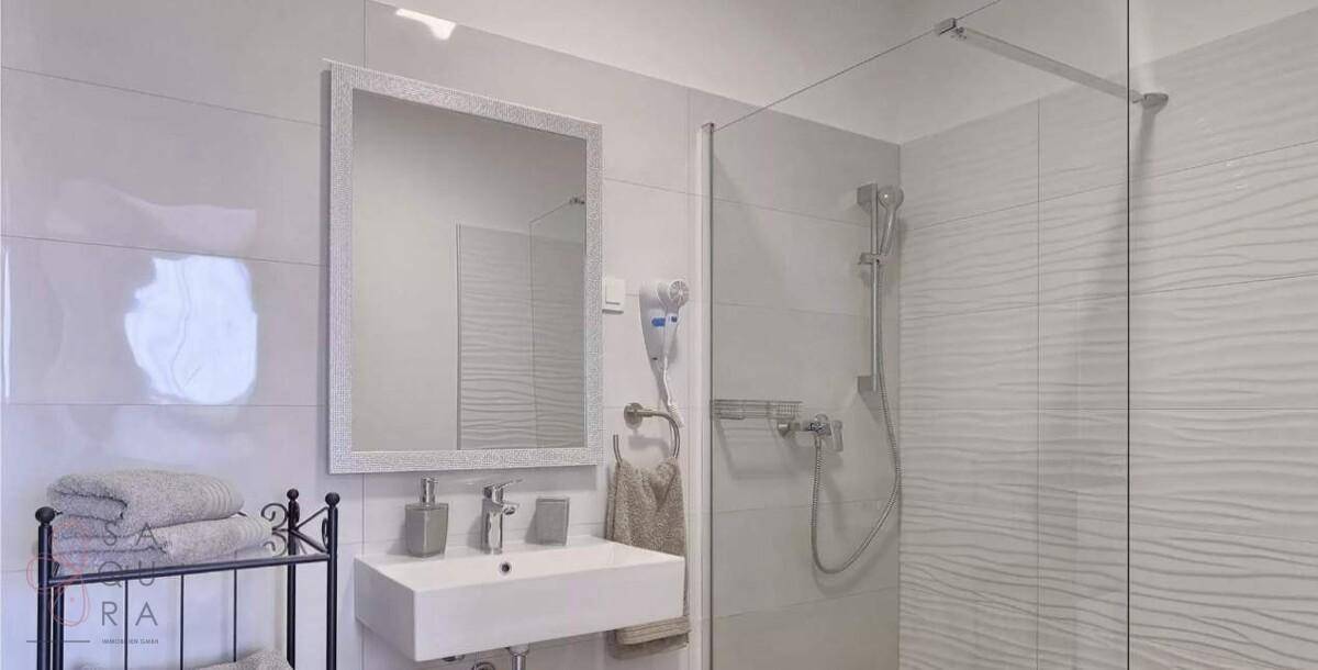 Modernes Badezimmer mit begehbarer Dusche, Einzelwaschbecken und großem Spiegel.
