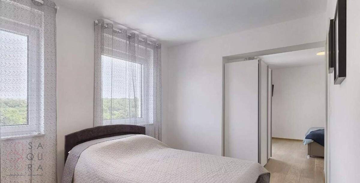 Gemütliches Schlafzimmer mit Einzelbett, Fenster und Schiebetür zu einem weiteren Raum.