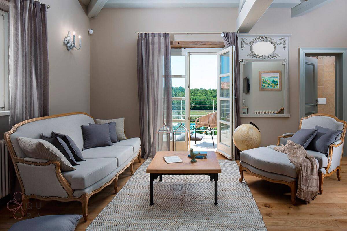 Helles Wohnzimmer im klassischen Stil mit Holzboden, bequemen Sofas und Balkonzugang.