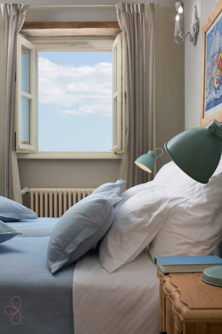 Detailansicht eines Schlafzimmers mit geöffnetem Fenster und Blick auf den blauen Himmel.