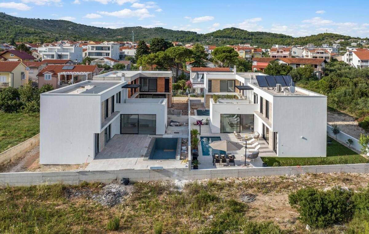 Luftaufnahme von mehreren modernen Villen mit Pools und Terrassen in einer Wohngegend.