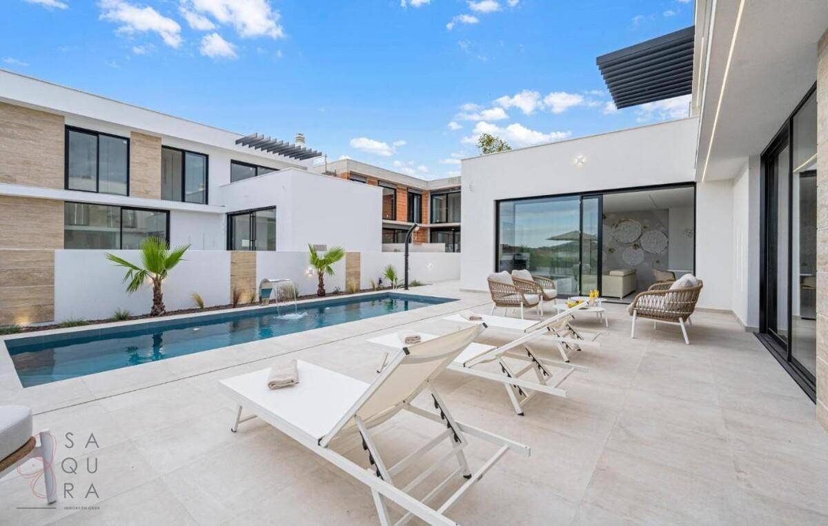 Elegante Poolterrasse mit Liegestühlen, Palmen und Blick auf weitere moderne Gebäude.