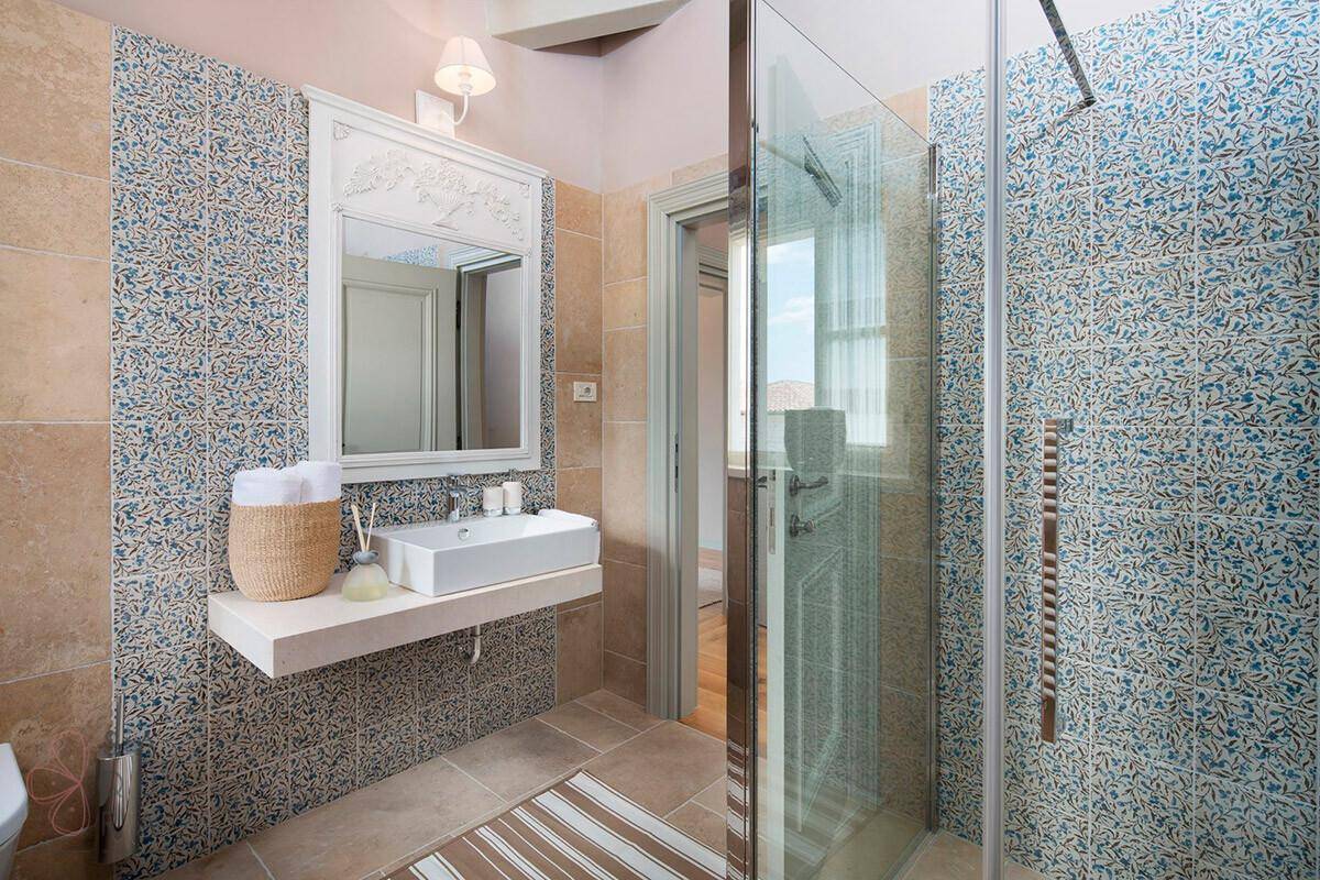Modernes Badezimmer mit stilvollen Fliesen, begehbarer Dusche und Einzelwaschbecken.