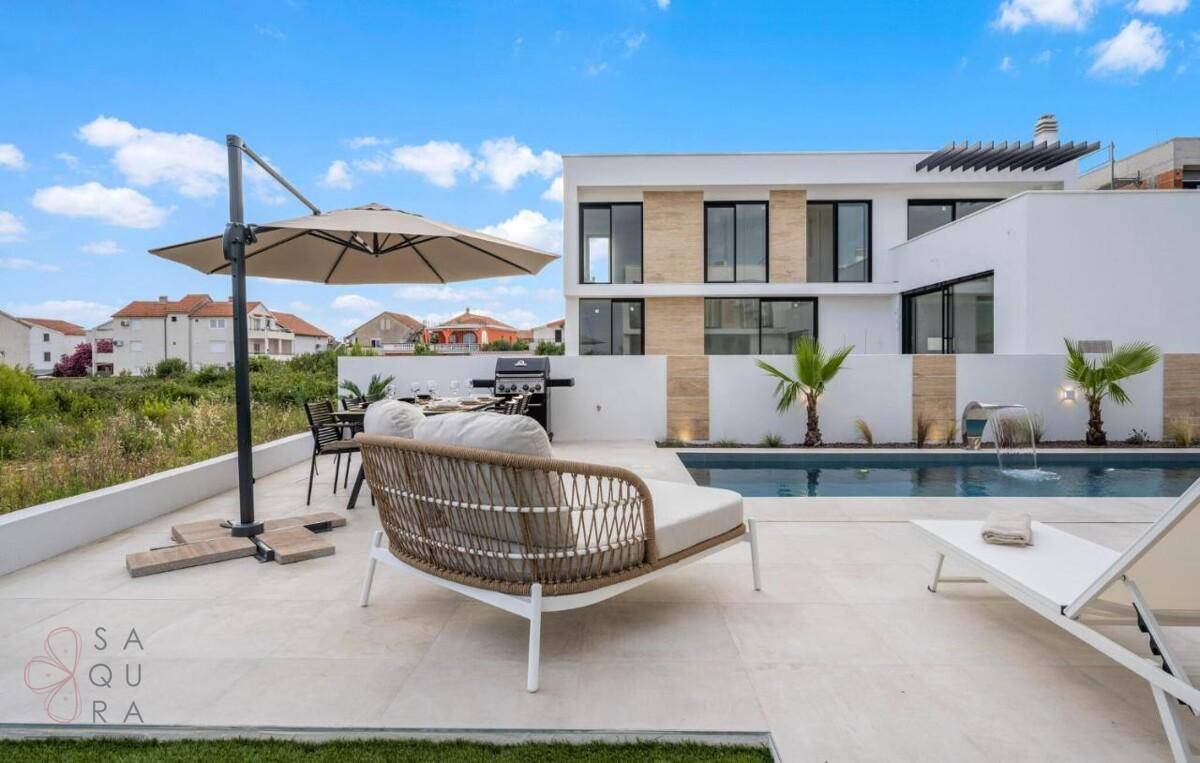 Geräumige Terrasse mit Essbereich, Lounge-Möbeln und Grill neben dem privaten Pool.