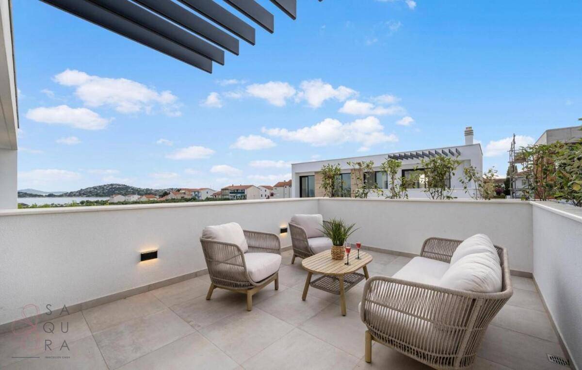 Heller Balkon mit bequemen Lounge-Möbeln und Panoramablick auf die Küstenlandschaft.