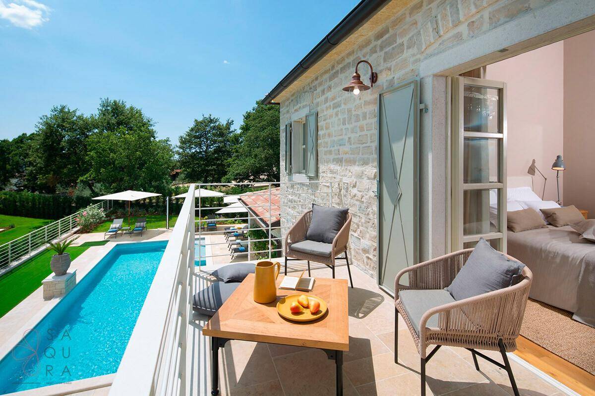 Gemütlicher Balkon mit Sitzgelegenheiten und Blick auf den Pool und die grüne Umgebung.