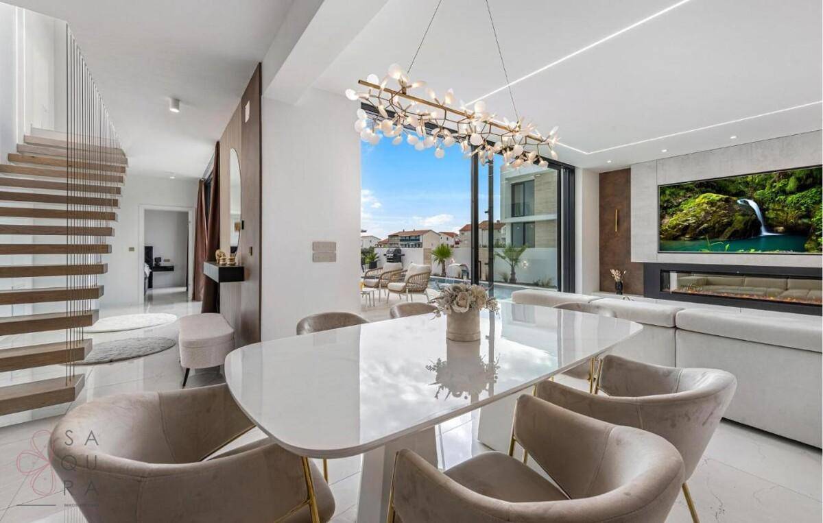Eleganter Wohn-Essbereich mit modernem Esstisch, Designer-Leuchte und Zugang zur Terrasse.