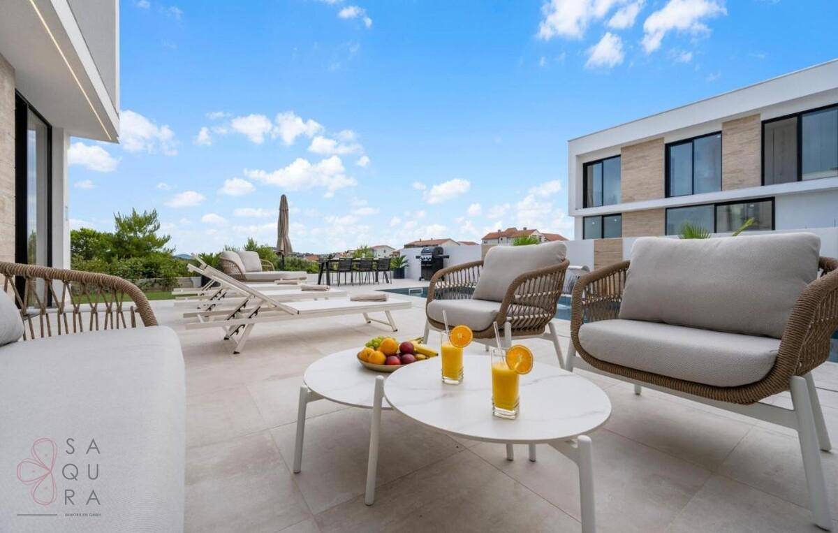 Sonnige Terrasse mit bequemen Lounge-Möbeln und erfrischenden Getränken am Poolbereich.