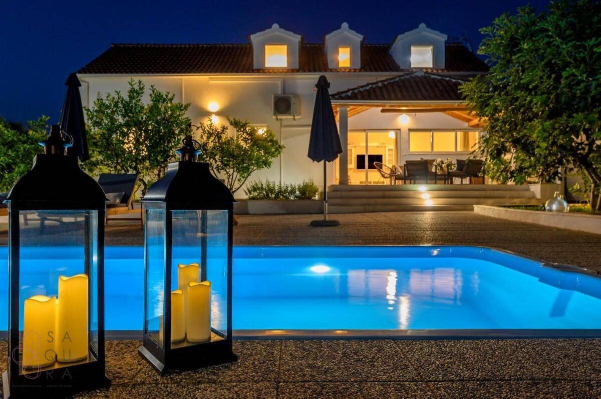 Nächtlicher Blick auf den beleuchteten Pool und die Hausfassade mit gemütlichen Laternen.