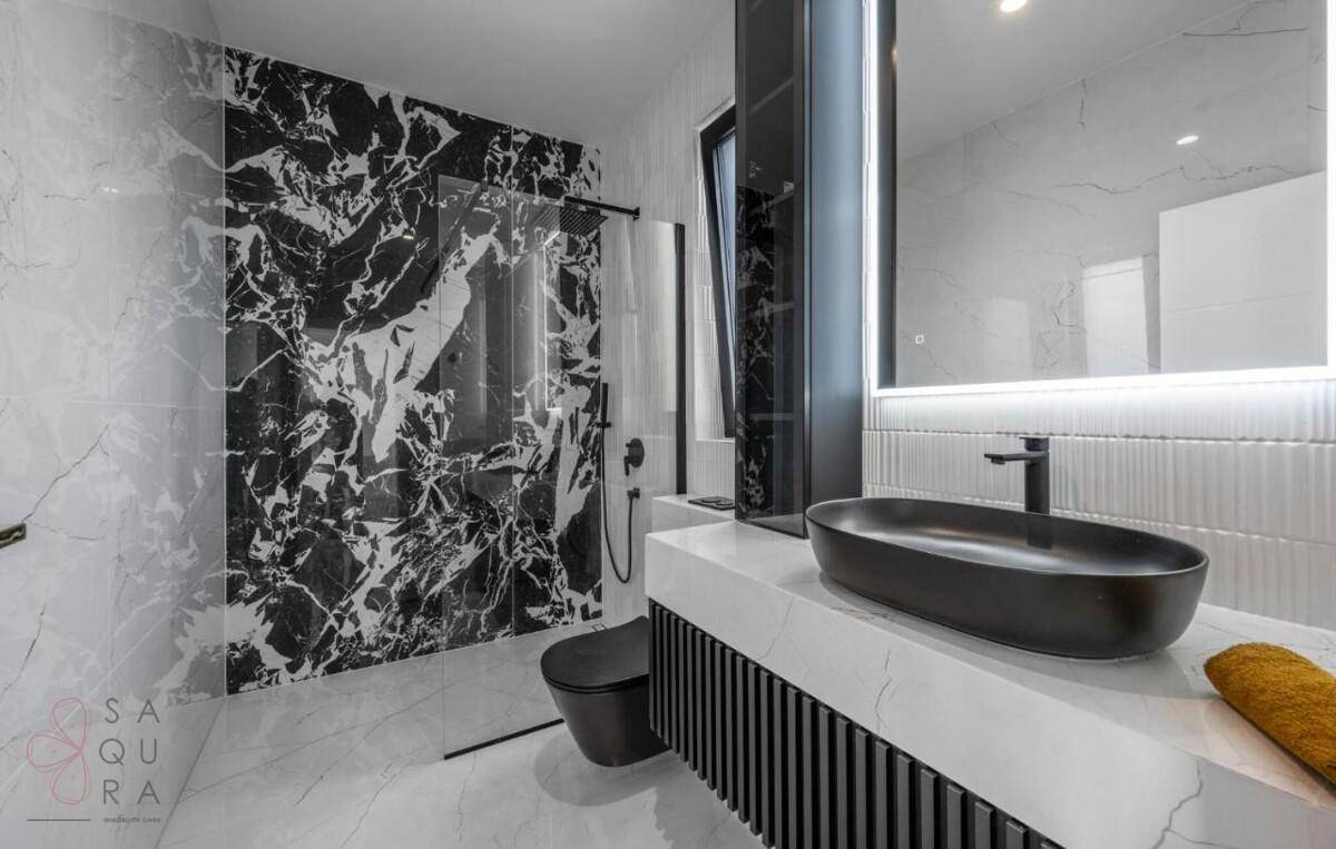 Luxuriöses Badezimmer mit schwarzem Marmor, begehbarer Dusche und modernem Waschtisch.