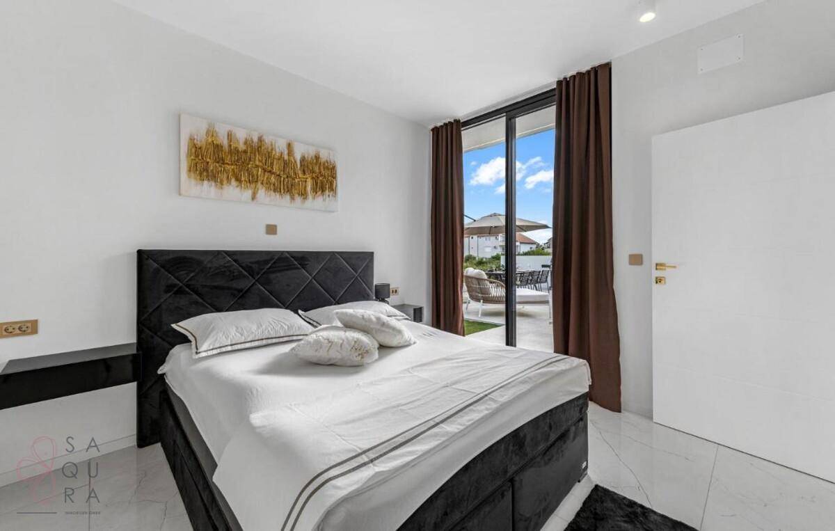 Elegantes Schlafzimmer mit dunklem Bett, Kunstwerk und direktem Zugang zur Außenterrasse.