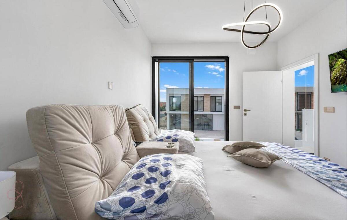 Komfortables Schlafzimmer mit Doppelbett, Klimaanlage und Blick auf die umliegenden Gebäude.