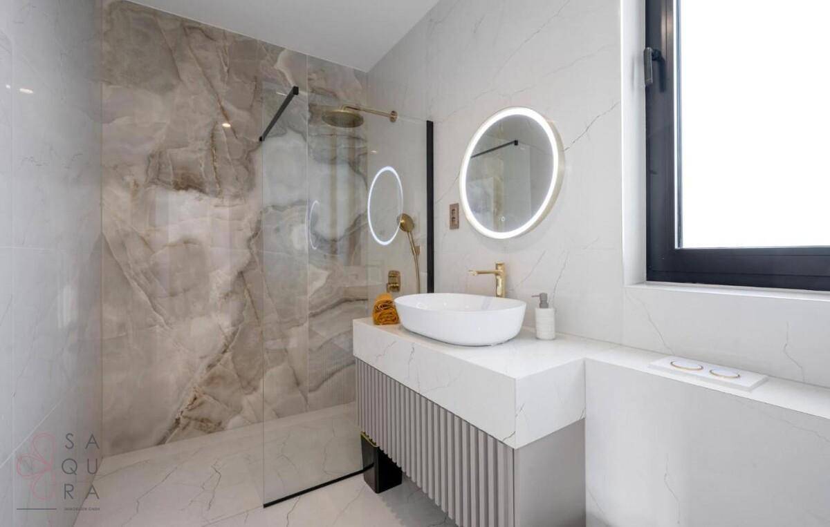 Modernes Badezimmer mit begehbarer Dusche, elegantem Waschtisch und beleuchtetem Spiegel.