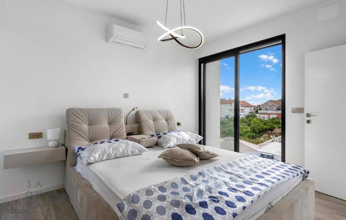 Helles Schlafzimmer mit Doppelbett, Klimaanlage und großem Fenster mit Blick ins Grüne.