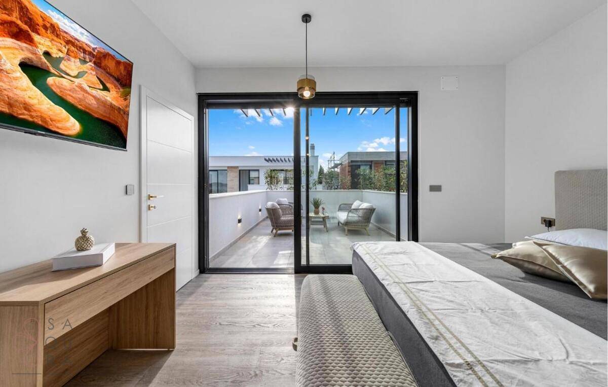 Modernes Schlafzimmer mit Balkonzugang, Holzboden und Blick auf die Umgebung.