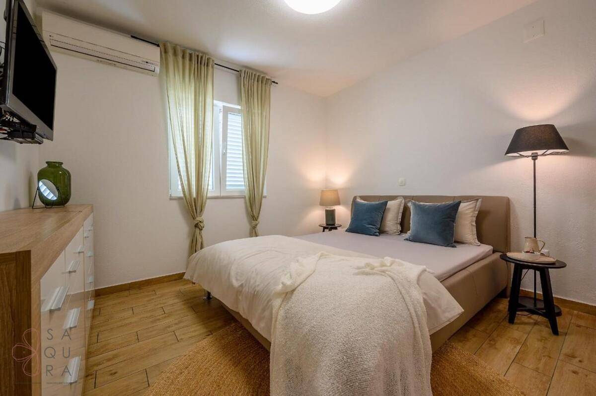 Helles Schlafzimmer mit Doppelbett, Holzboden und Klimaanlage.