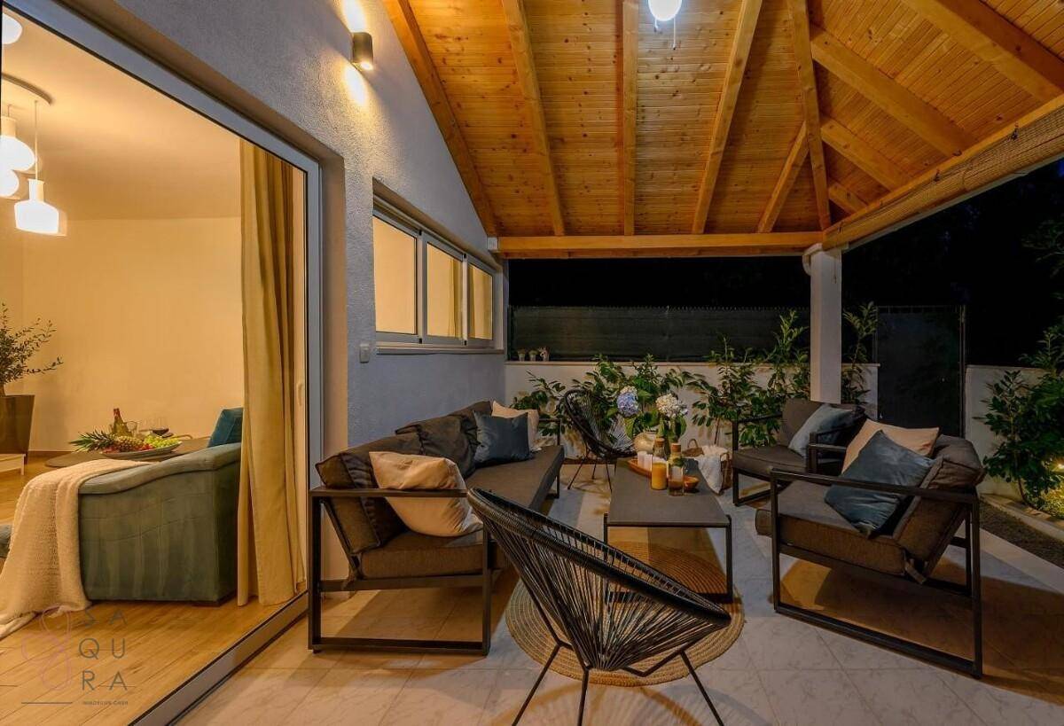 Überdachte Terrasse mit bequemen Lounge-Möbeln und Holzdach, ideal für entspannte Abende.