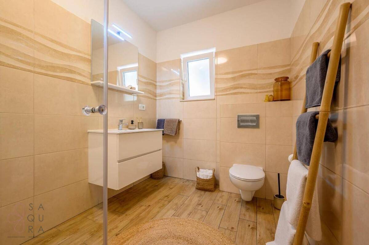Modernes Badezimmer mit begehbarer Dusche, schwebendem Waschtisch und Fenster.