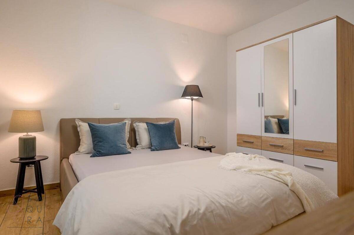 Gemütliches Schlafzimmer mit Doppelbett, Kleiderschrank und Holzboden.
