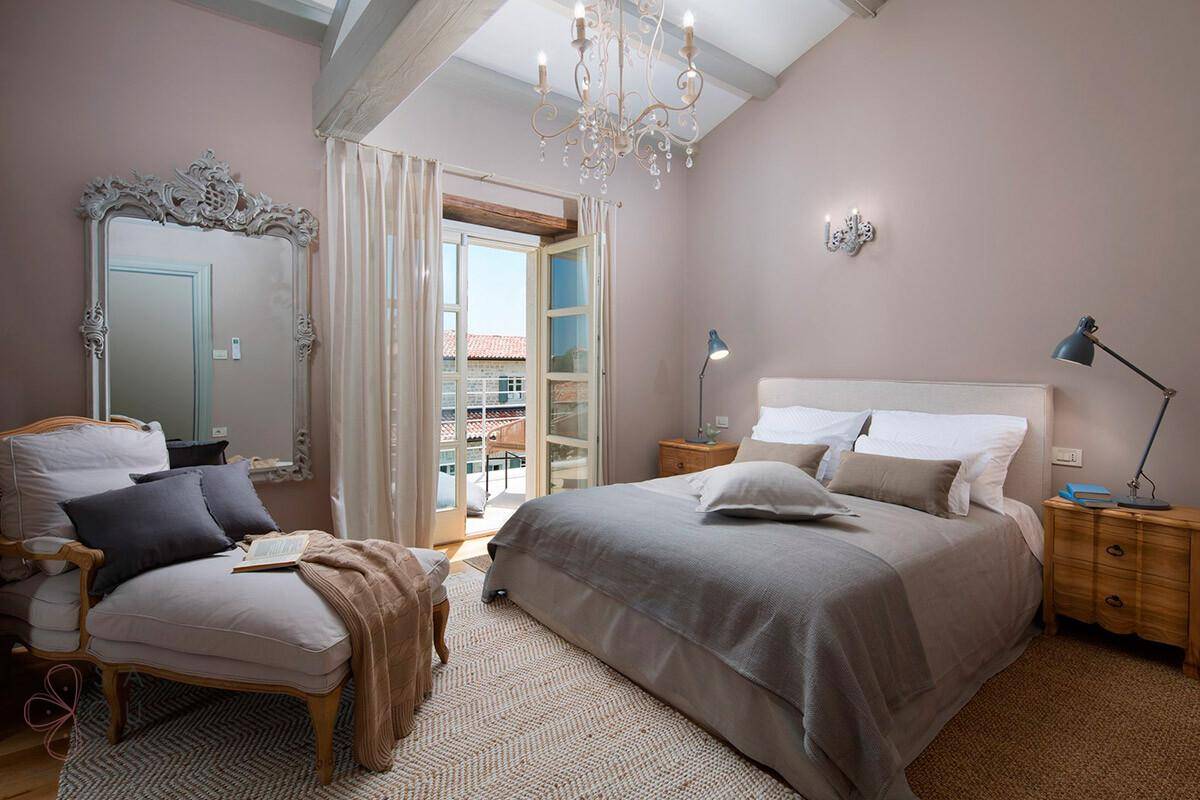 Elegantes Schlafzimmer mit Doppelbett, Holzboden, Balkonzugang und großem Spiegel.