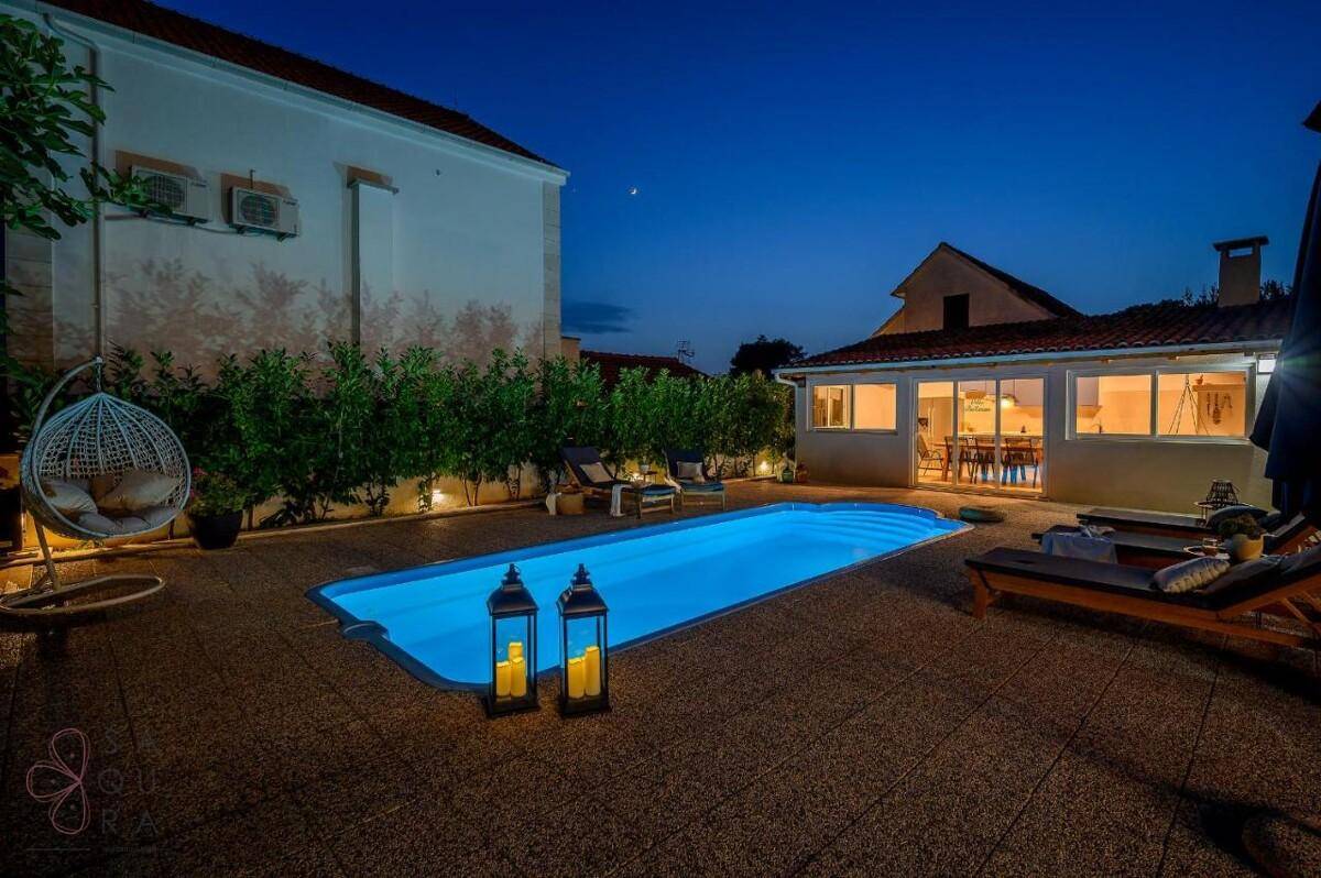 Entspannender Poolbereich mit Hängesessel, Liegestühlen und Laternen in der Abendstimmung.