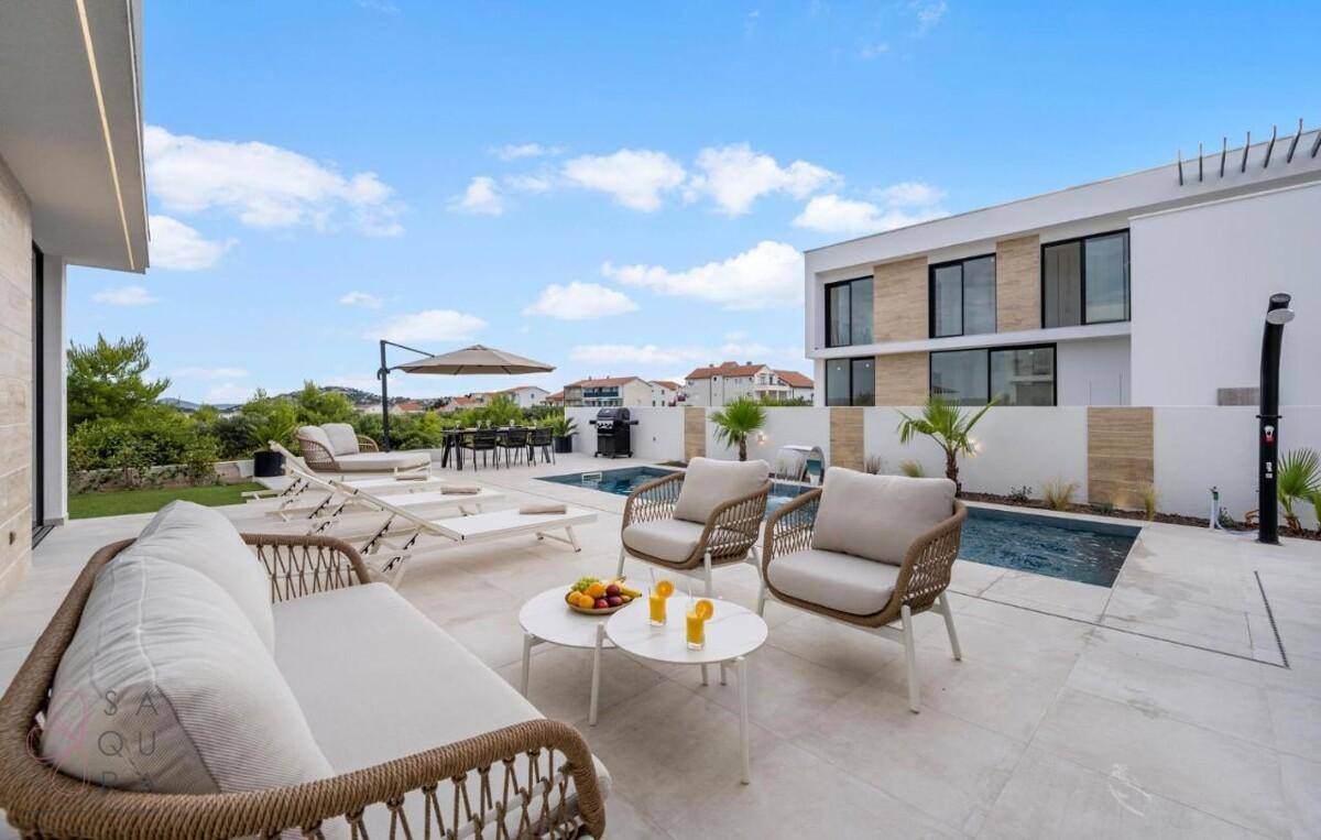 Entspannter Lounge-Bereich am Pool mit bequemen Möbeln und Blick auf die moderne Architektur.