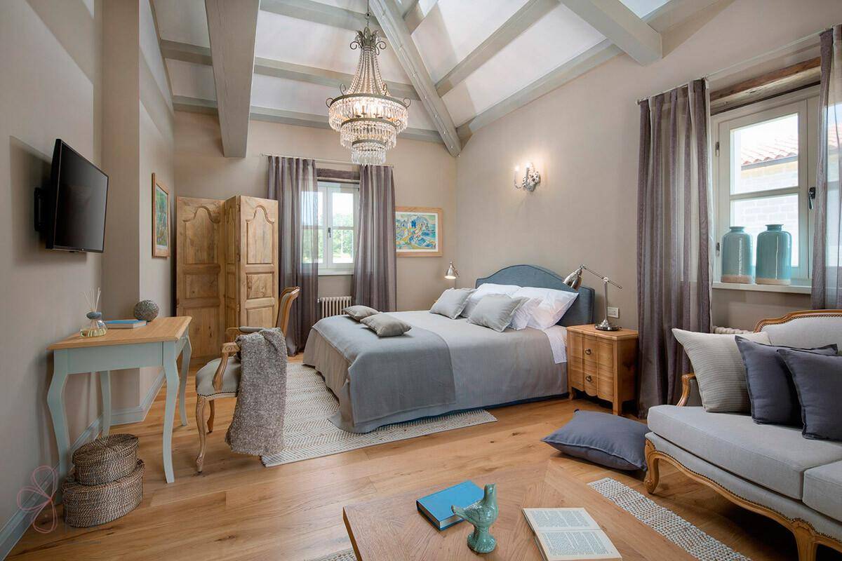 Geräumiges Schlafzimmer mit Doppelbett, Holzboden, Holzbalkendecke und klassischer Einrichtung.