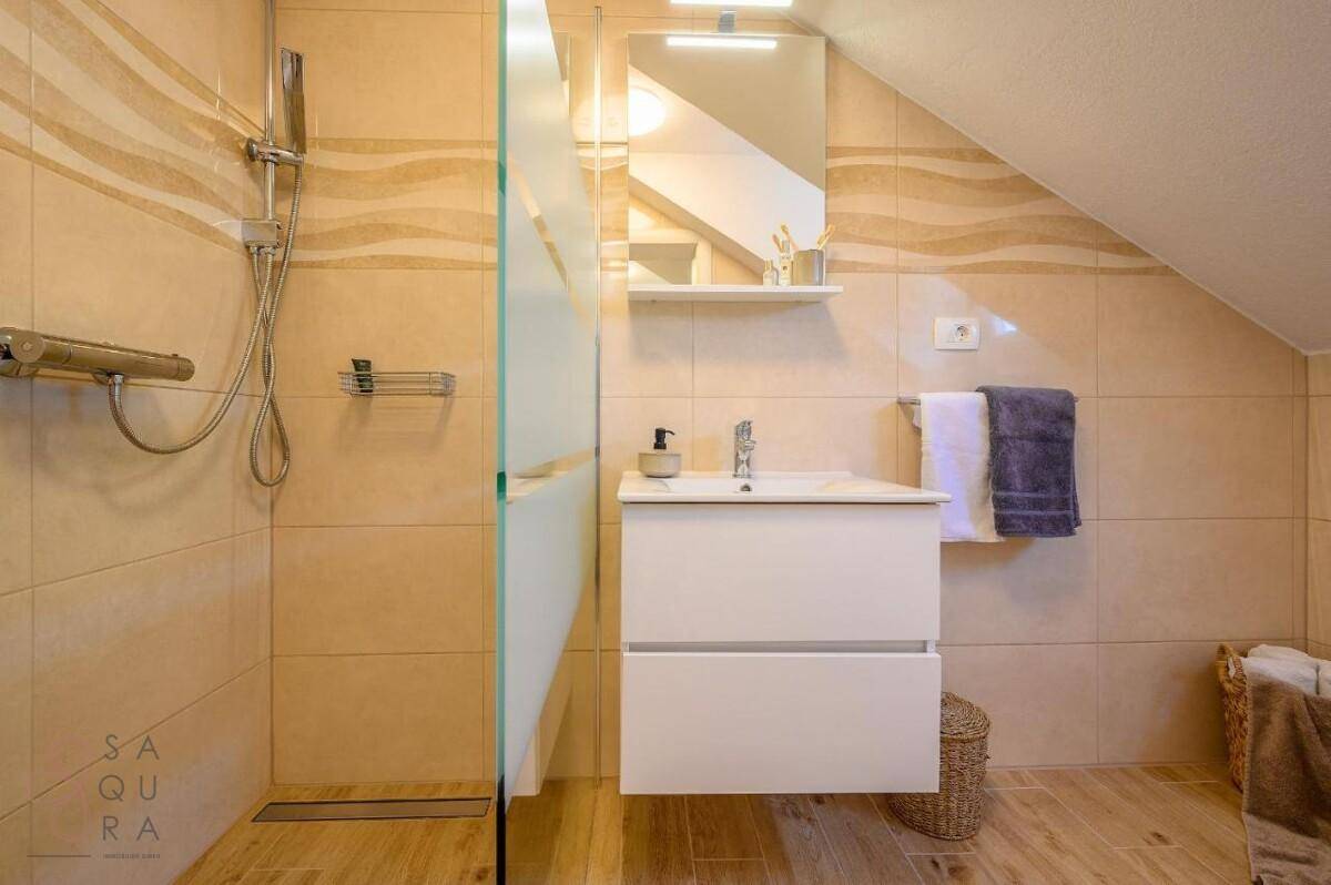 Modernes Badezimmer im Dachgeschoss mit Dusche, Waschtisch und schräger Decke.