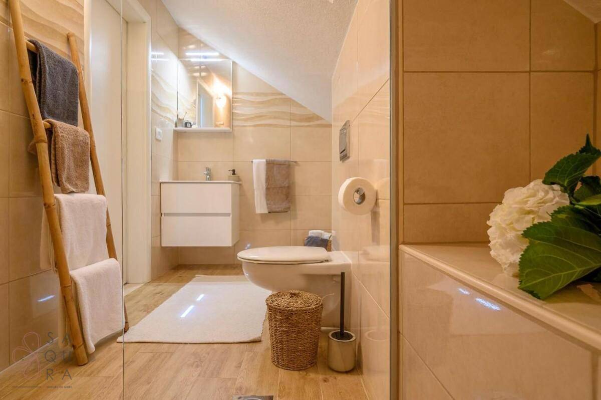 Modernes Badezimmer im Dachgeschoss mit Toilette, Waschtisch und Handtuchleiter.