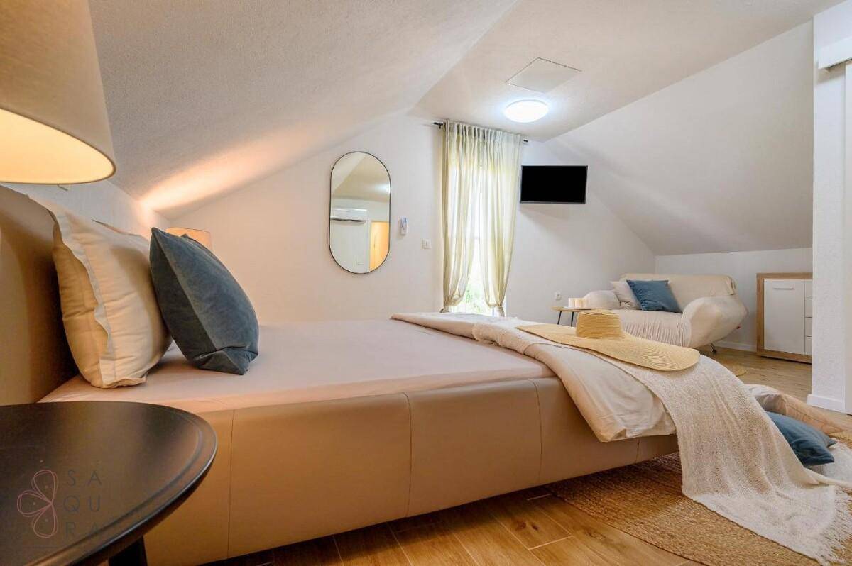 Gemütliches Schlafzimmer im Dachgeschoss mit Doppelbett, Sofa und schräger Decke.
