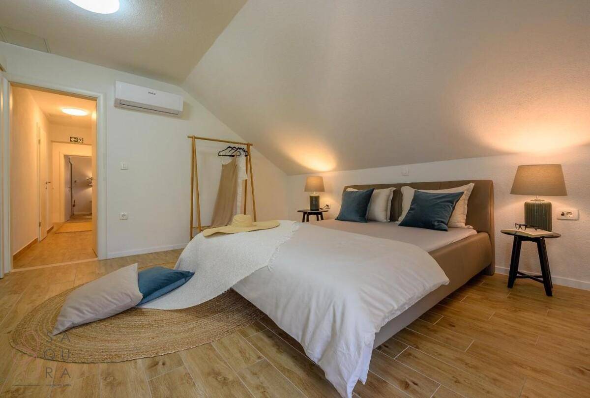 Geräumiges Schlafzimmer im Dachgeschoss mit Doppelbett, Holzboden und Klimaanlage.