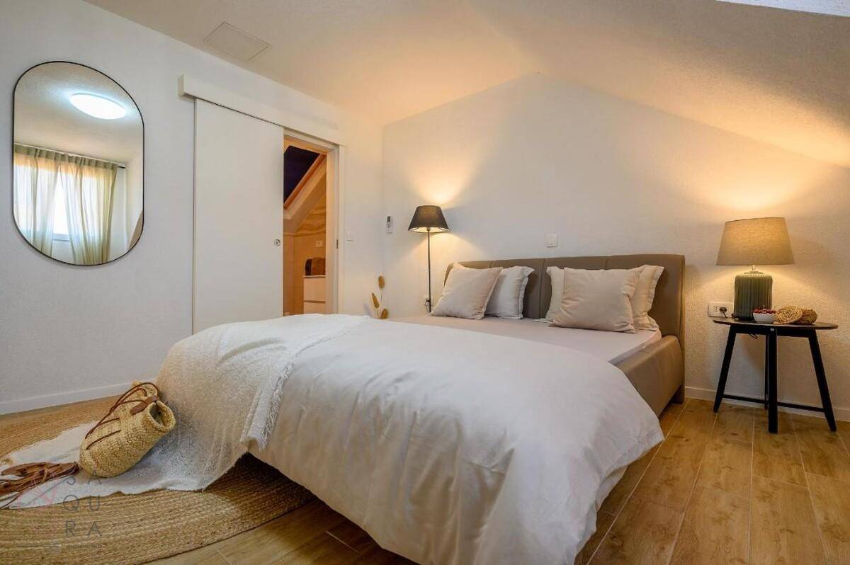 Helles Schlafzimmer im Dachgeschoss mit Doppelbett, Holzboden und Schiebetür.