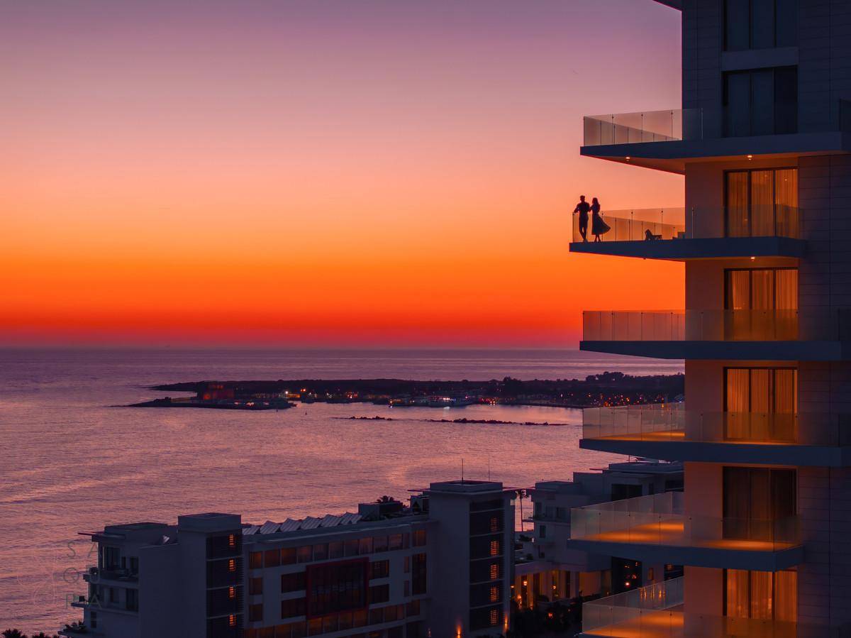 Gebäude mit Balkonen bei Sonnenuntergang, bietet einen atemberaubenden Blick auf das Meer und die Küste.