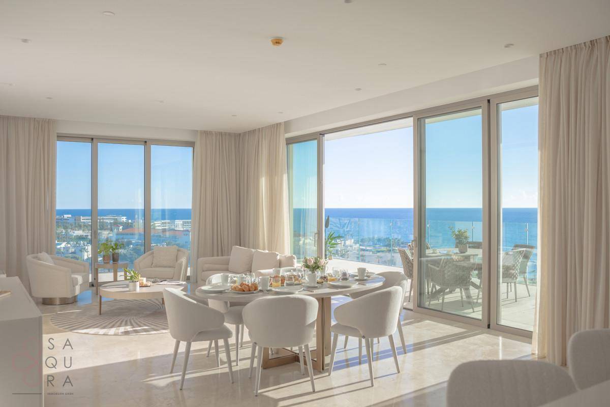 Heller Wohn- und Essbereich mit Panoramablick auf das Meer und direktem Zugang zur Außenterrasse.