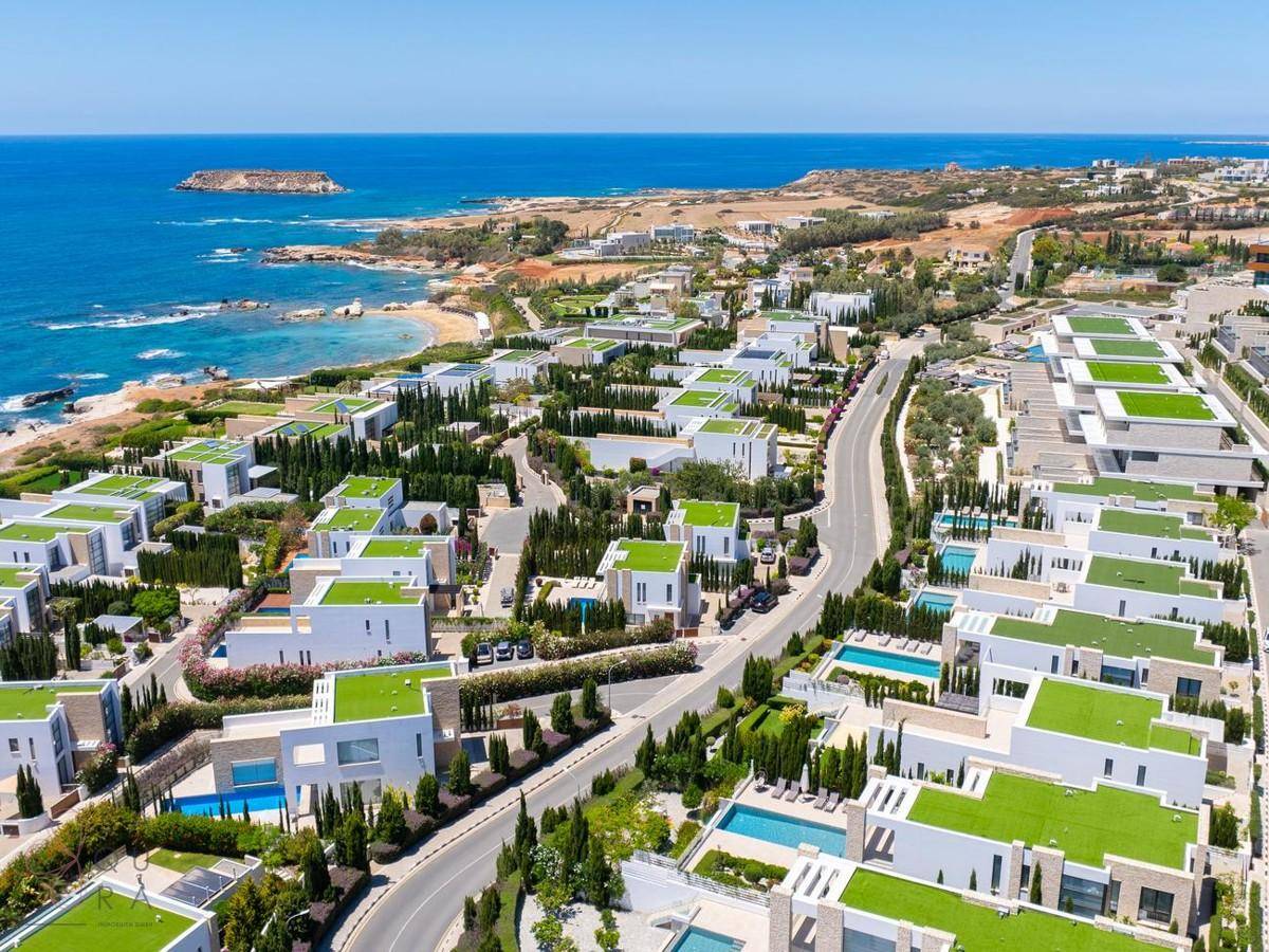 Weitläufige Wohnanlage mit modernen Villen, grünen Dächern und Blick auf das Mittelmeer.