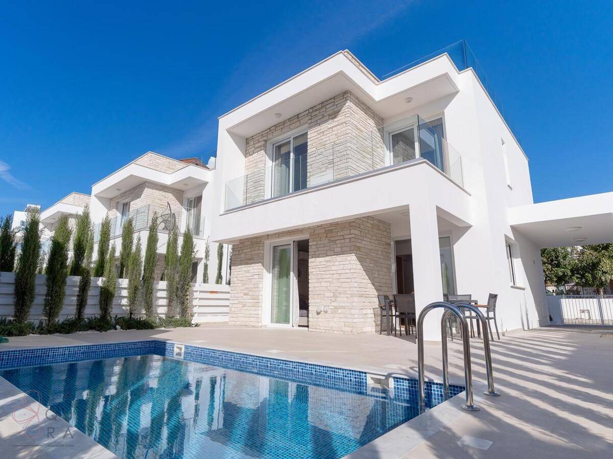 Moderne Villa mit privatem Pool und Steinfassade unter strahlend blauem Himmel.
