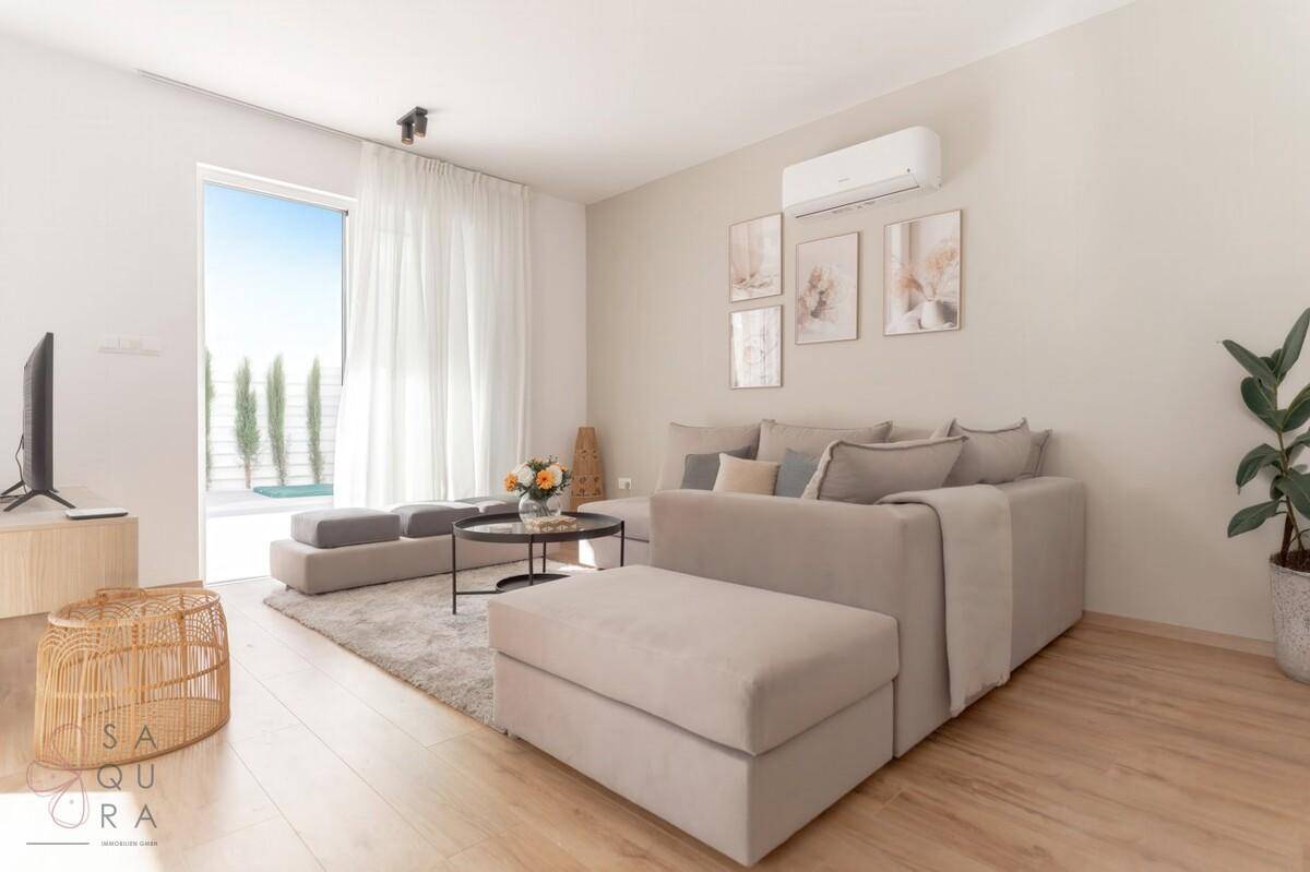 Modernes Wohnzimmer mit hellem Holzboden, Klimaanlage und großem Fenster.