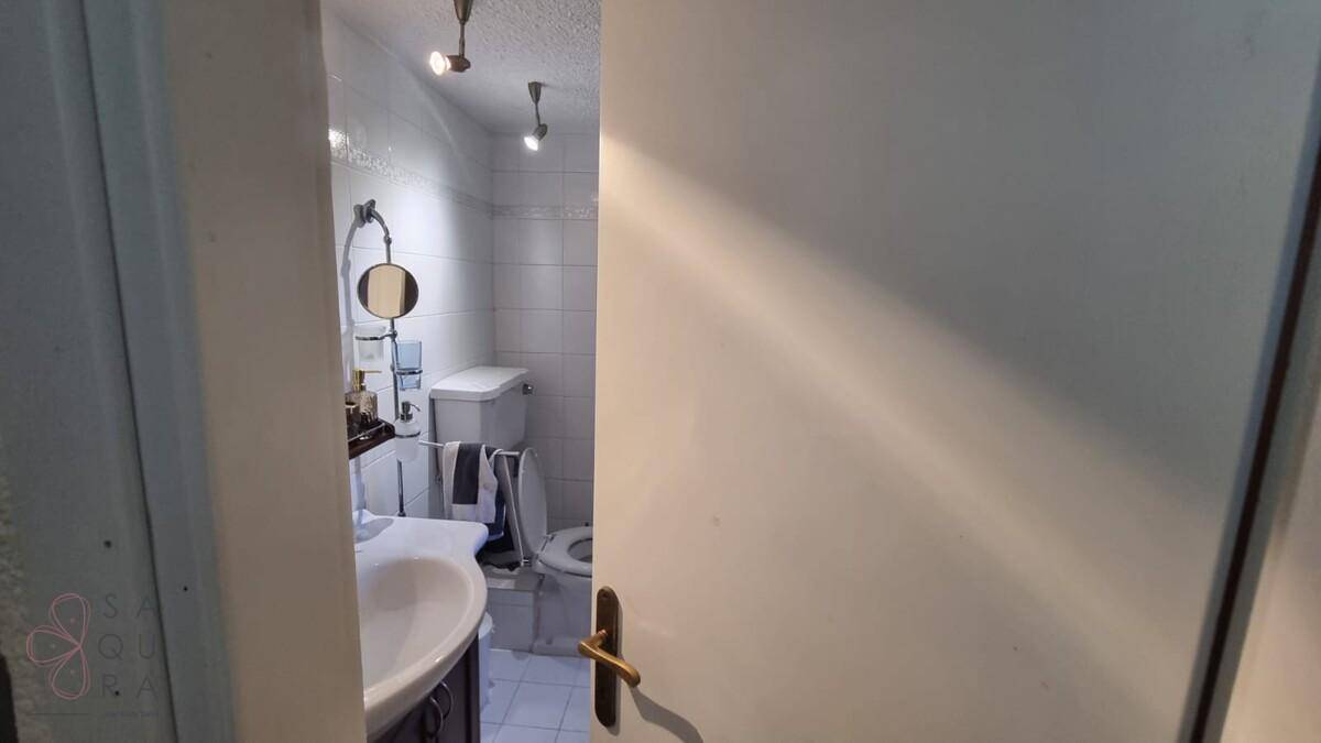 Badezimmer mit Waschbecken, Spiegel und Toilette, hell gefliest und funktional eingerichtet.