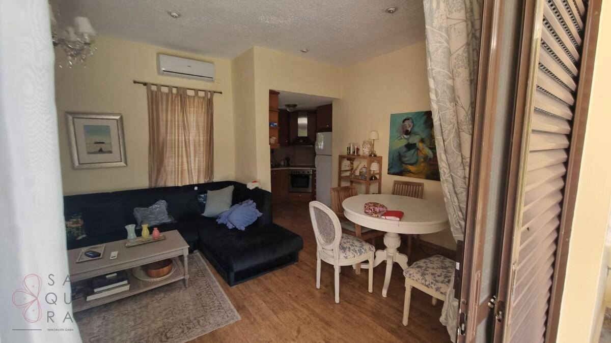 Heller Wohn- und Essbereich mit Holzboden, bequemer Couch und Blick in die angrenzende Küche.