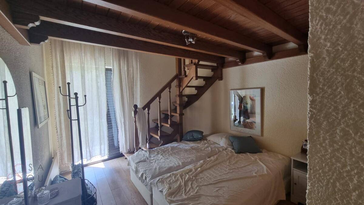 Schlafzimmer mit zwei Betten, sichtbaren Holzdeckenbalken und einer charmanten Holztreppe.