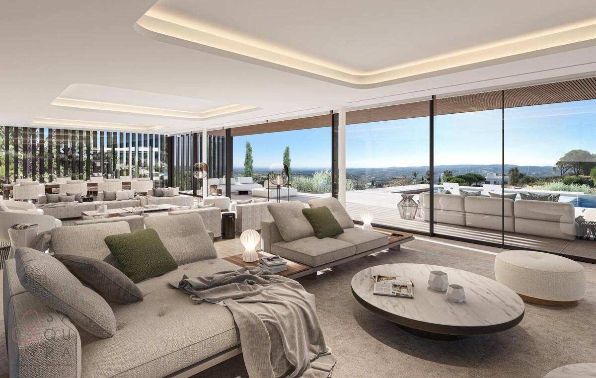 Helles, offenes Wohnzimmer mit großen Fenstern, die einen weiten Blick auf die Landschaft bieten.